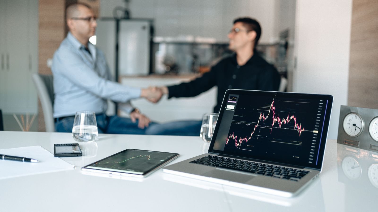 Business handshake beside a laptop showing growth charts after an upgrade conversation.